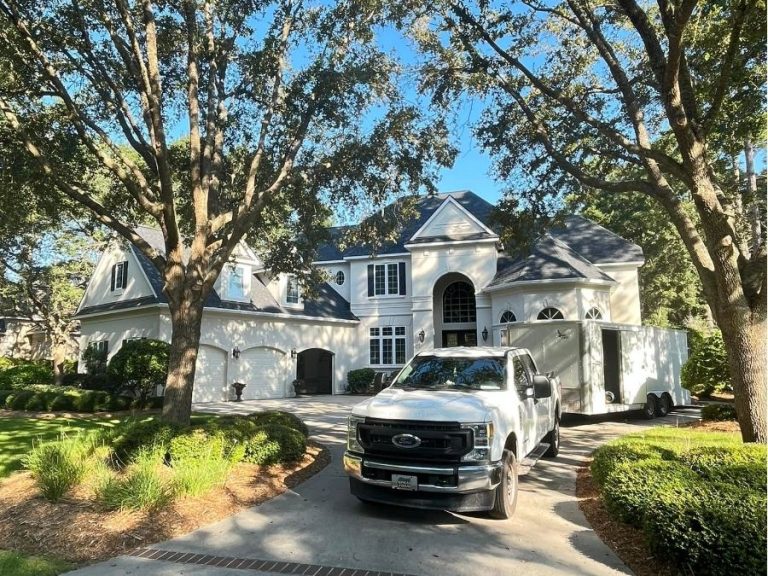 Large white custom home in Bluffton, SC, featuring a grand arched entryway, multiple gables